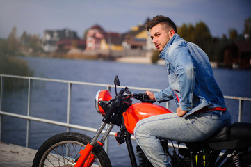 Obraz premium large portrait of a young sporty fashionable man on a motorcycle, a warm shot, late autumn