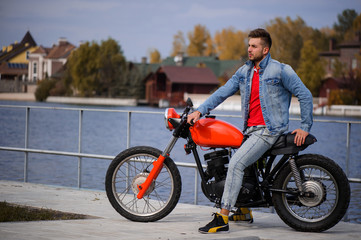 large portrait of a young sporty fashionable man on a motorcycle, a warm shot, late autumn