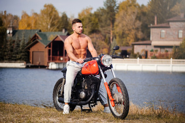 young sports fashionable man with a naked torso, fitness coach on a motorcycle, a warm shot, late autumn