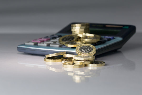 Pound Coins Stacked and Falling - Reflective Surface, Grey Background