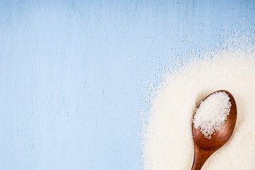 Wooden spoon with sugar on a blue  background