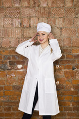 Portrait of a good looking young blond nurse with her arms crossed in a white background