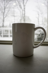 Obraz premium White Coffee Cup in Front of Snowy Window