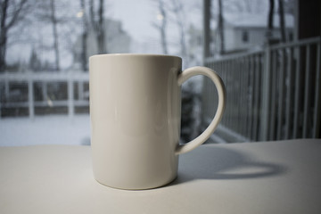 Obraz premium White Coffee Mug in front of snowy window