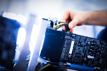 Man's hand plugging a wire in an input.