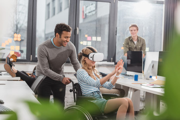 woman in wheelchair using virtual reality glasses at modern office
