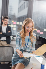 Obraz premium young woman looking at folder with documents at modern office