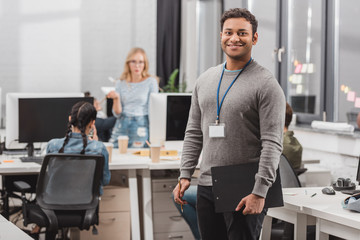 happy african american man with name tag and planchette at modern office