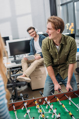 cheerful office workers playing in table soccer at modern office