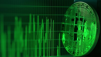 Shiny bitcoin reflects green data graph on the computer screen. Cryptocurrency related shot