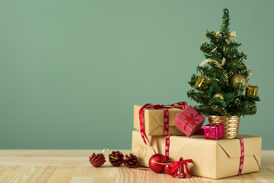 Christmas background. A small Christmas tree and boxes with gifts on a wooden table. Green background. Space for text. New Year's background.