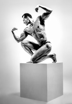 athletic guy - bodybuilder,   pose on gray background