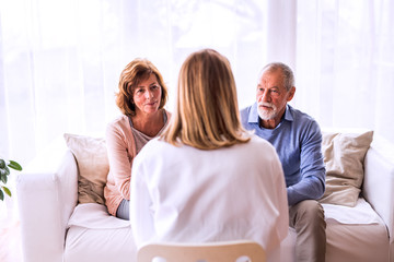 Obraz premium Female doctor talking to a senior couple.