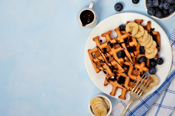 Homemade waffles for breakfast with blueberries and banana with chocolate sauce. Good morning!