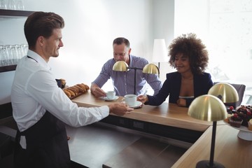 Waiter serving coffee to costumer at counter