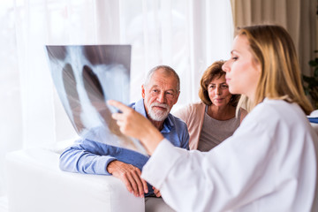 Female doctor with x-ray talking to a senior couple.