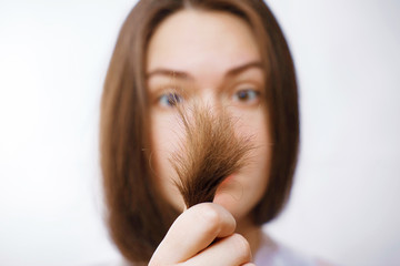 girl looks at damaged hair tips, split hair, girl looks at her hair, hair in the foreground