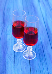 Two glasses with homemade red wine on blue boards outdoors in a countryside at summer.