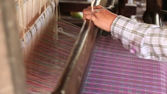 Traditional Burmese textile manufacture in craft village where old women work on wooden weaving loom machines and spin yarn creating silk or cotton fabric. Inle Lake, Myanmar. Burma