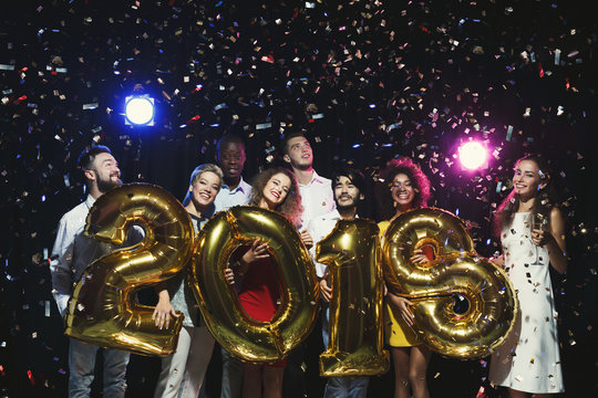 Group of young happy friends with number balloons at new year party