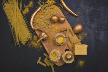 Italian food .Golden ingredients for cooking pasta with board on dark background.Top view