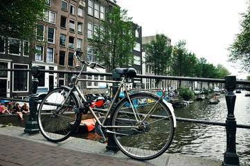 Fototapeta premium Old bicycle standing next to canal. Amsterdam cityscape