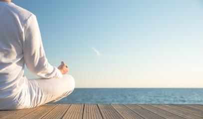 Junger Mann macht Yoga Position am Strand. Sonnenuntergang. Wunderschöner Blick aufs Meer