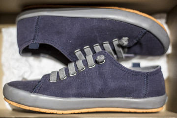 Obraz na płótnie Canvas Stylish blue sneakers are stored inside a cardboard box. Close-up.
