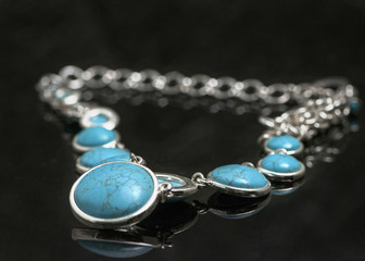 Turquoise necklace with silver chain on black background