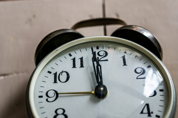 A close-up of a clock showing 12.00 hours on rustick bacground. Concept New Year.