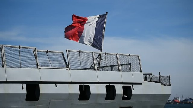 French frigate tied to a dock  in a harbor 