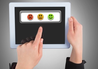 Hands holding tablet with feedback smiley satisfaction icons
