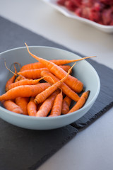 Small baby carrots in soup plates close up