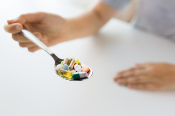 close up of female hand holding spoon with pills