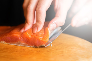 cook cuts red fish on a wooden board