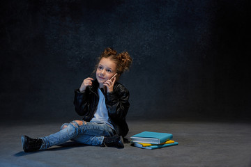 Little girl sitting with smartphone in studio