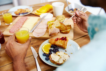 close up of man eating croissant with orange juice