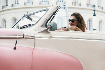 Beautiful woman tourist driving a classic car in Cuba.