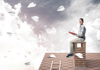 Handsome student guy reading book and paper planes flying in air