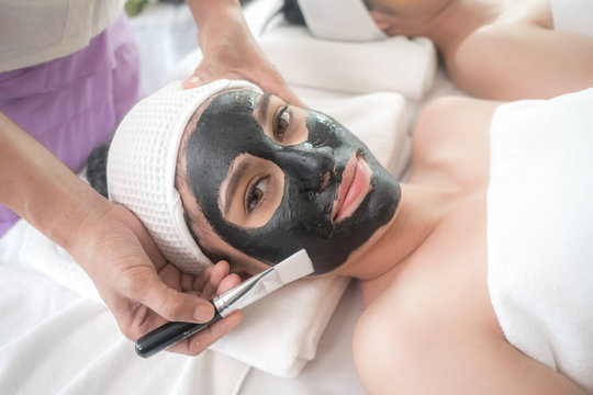 beautiful and healthy young woman relaxing with face massage skin care health black mask at beauty spa salon