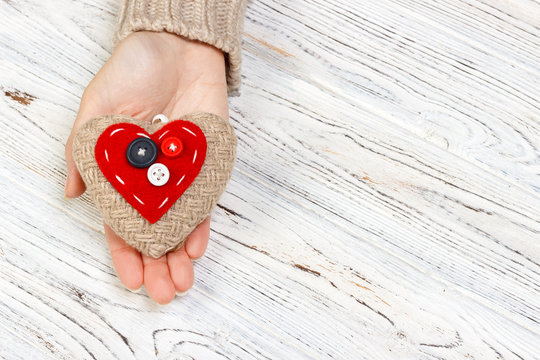 red heart in hands closeup on wooden background. Valentine's Day concept with copyspace