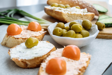 Bruschetta with soft cream cheese, olives and cherry tomatoes. Vegetarian breakfast.