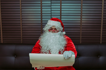 Fototapeta premium Santa Claus using a magnifying glass to look at the address of the children to bring gifts to send tonight.