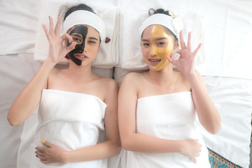 couple beautiful and healthy young woman relaxing with face massage skin care health black mask and gold mask at beauty spa salon