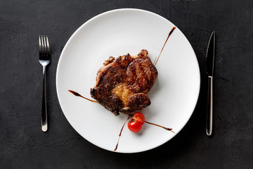 Rib eye steak on white plate, top view