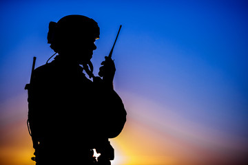 Silhouette of military soldier with weapons at sunset. shot, holding gun, colorful sky. military...