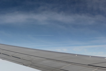 Naklejka na ściany i meble A passenger plane wing against a blue sky and white clouds