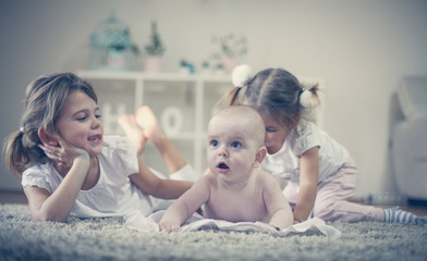 Sisters have play with baby brother.