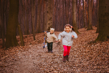 Little boy and girl walk with willow branches outside in the rays of evening sun