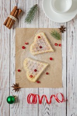 Two cookie hearts with powdered sugar and cranberries on crumpled paper